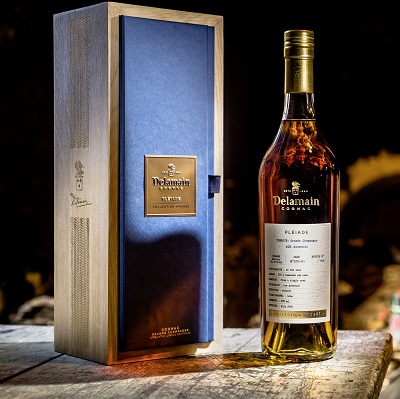 Eine elegant präsentierte Flasche Delamain Cognac steht neben einer stilvollen Holzbox mit blauer Innenseite. Der Cognac hat eine goldene Farbe, umgeben von dunklem Holz.